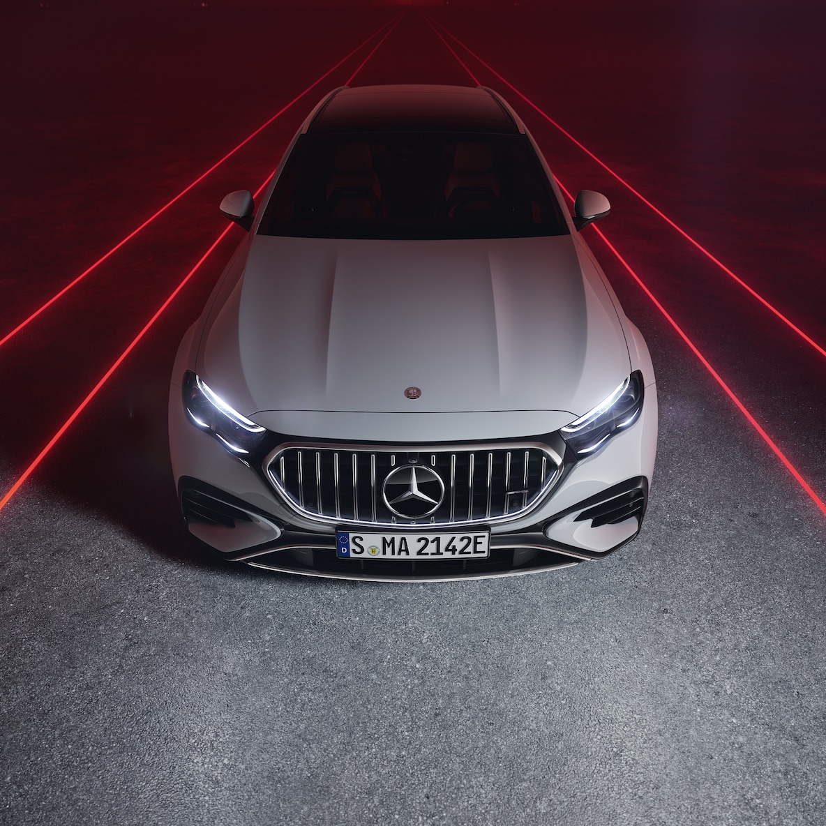 Ön görünümde kırmızı bir arka planda Mercedes-AMG E 53 HYBRID 4MATIC+, üstten görünüm.