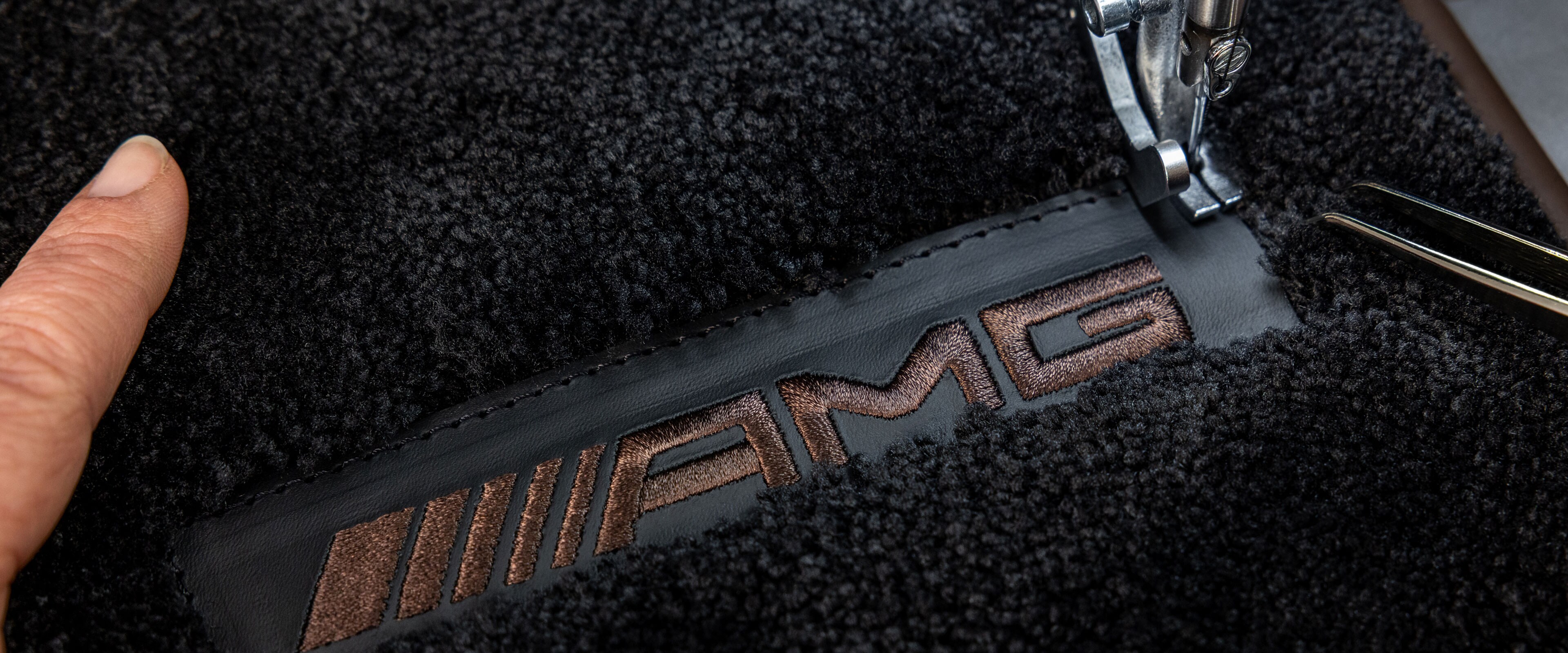 Mercedes-AMG'de koyu renkli yüzey üzerinde MANUFAKTUR yazısı.