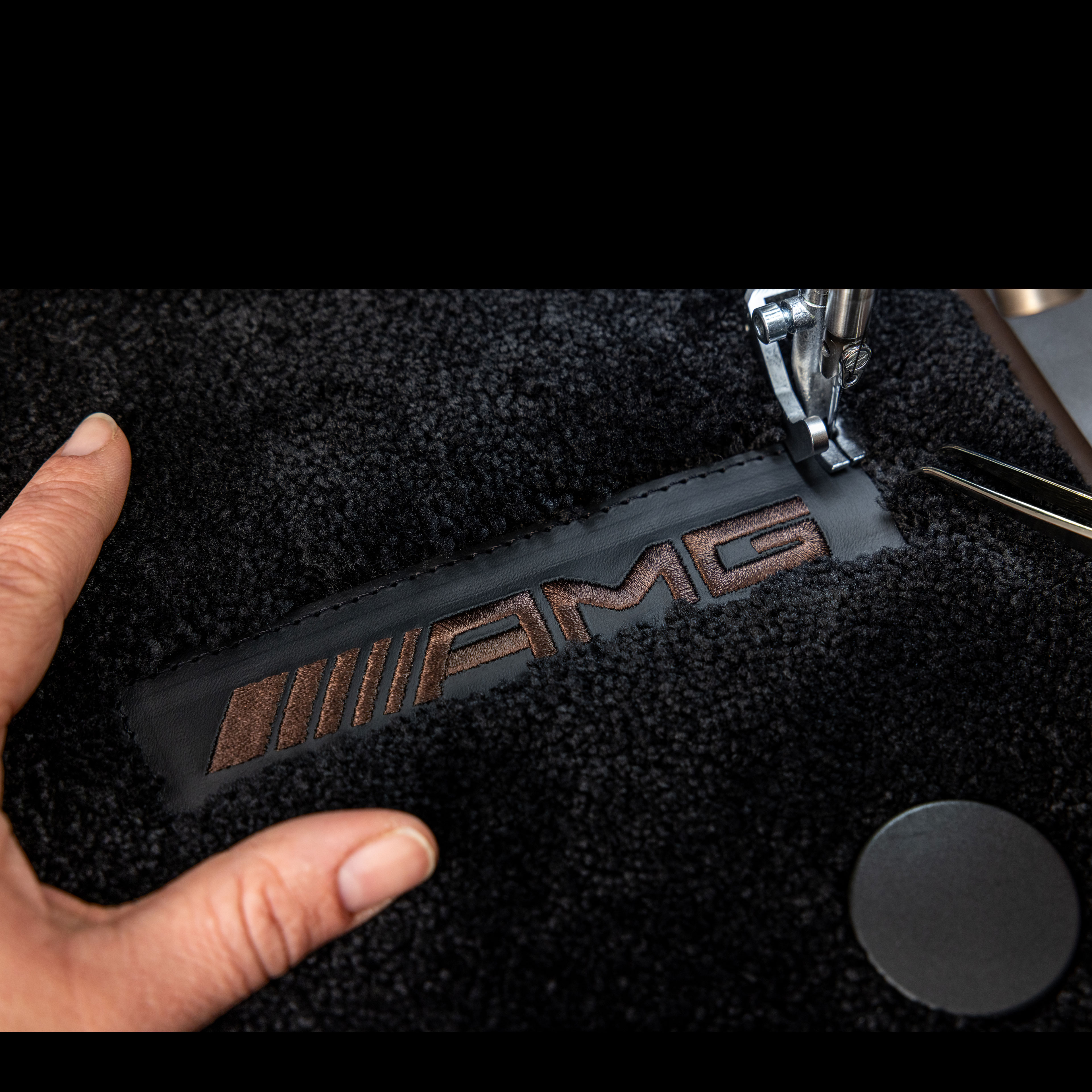 MANUFAKTUR | Mercedes-AMG Mercedes-AMG'de koyu renkli yüzey üzerinde MANUFAKTUR yazısı.