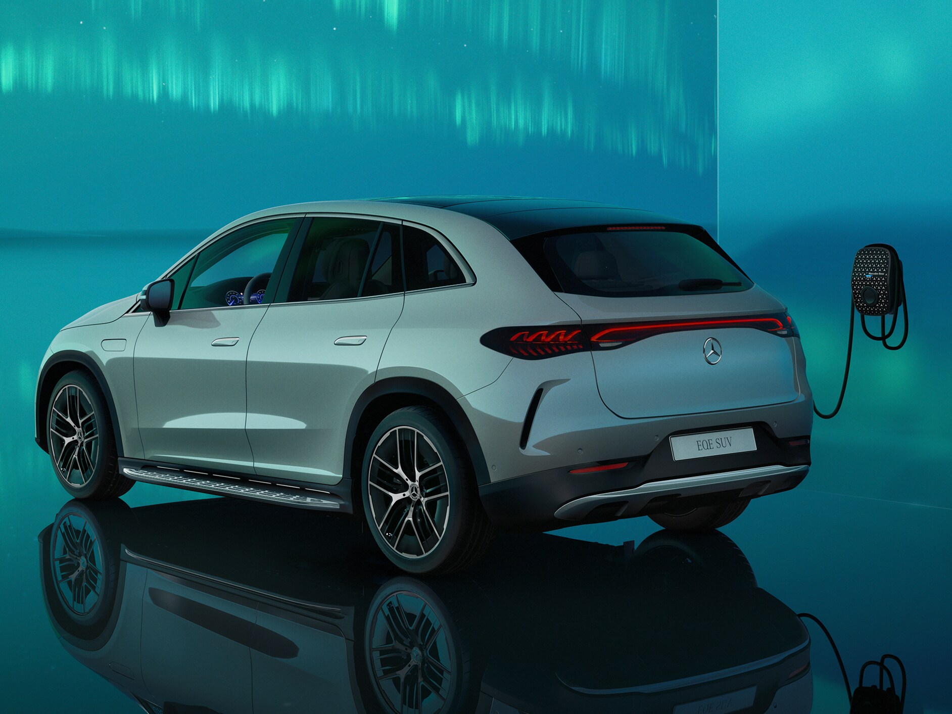 Bir Mercedes Benz duvar tipi şarj ünitesinde şarj olan EQE SUV'nin arka yan perspektiften görünümü.