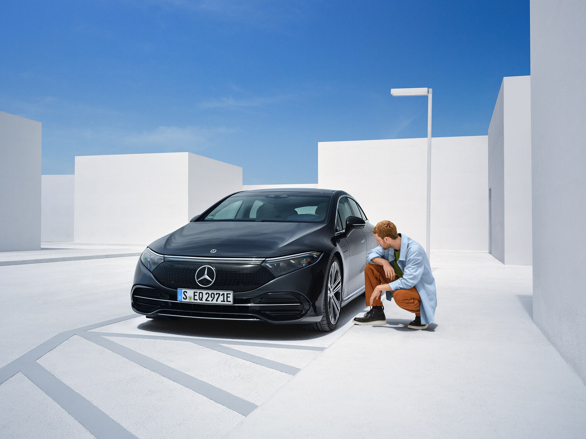 Kontrol etmek için Mercedes-Benz'inin yanında diz çöken bir adam