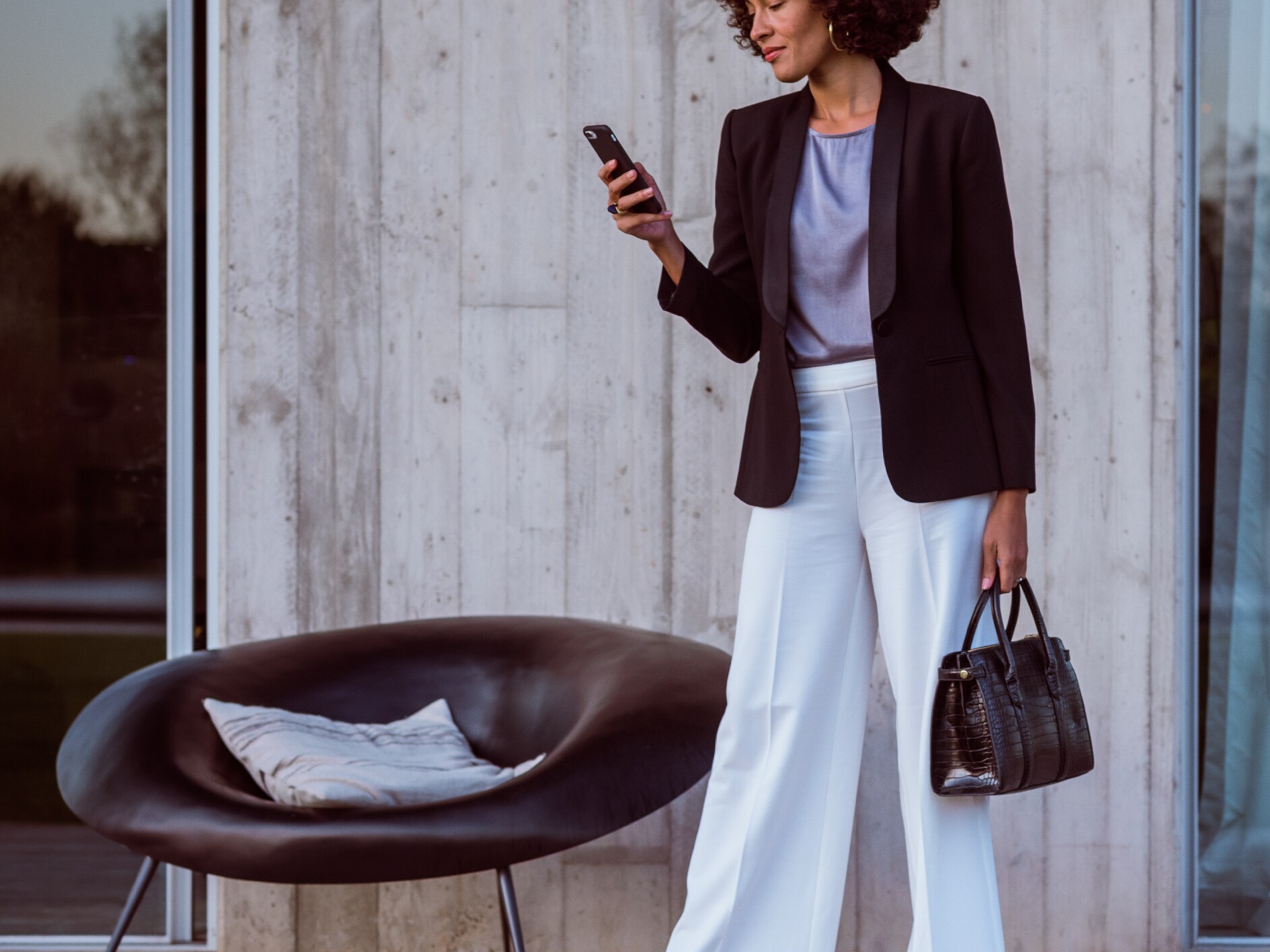 Bir kadın akıllı telefon, Mercedes-Benz Uygulaması ve Mercedes me ID'si üzerinden Mercedes Benz'ine bağlanıyor.