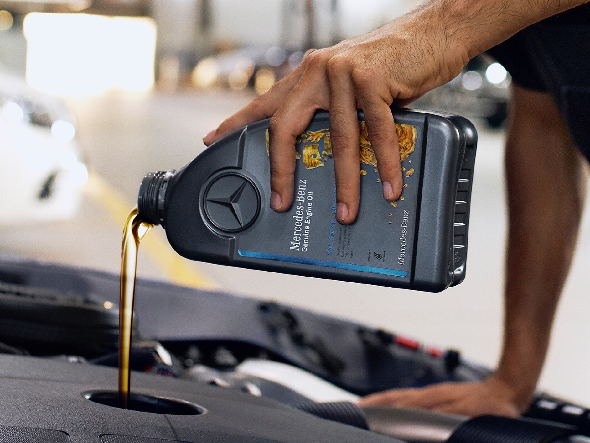Bir Mercedes-Benz aracına motor yağ dolduran bir kişi.