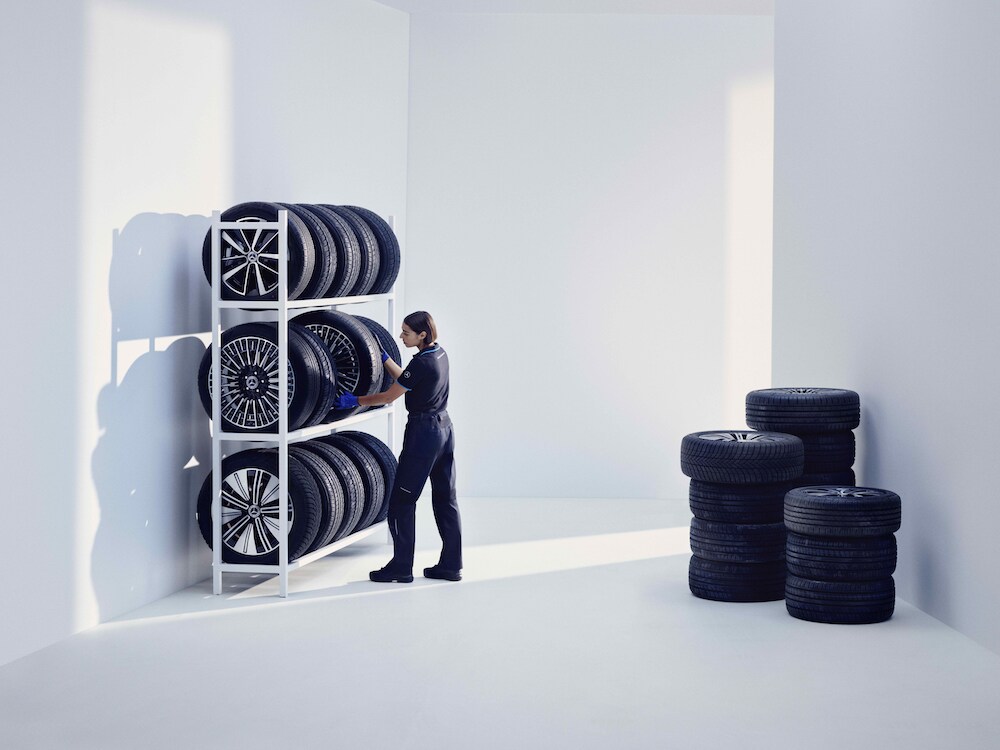 Bir Mercedes-Benz araç, jantların saklandığı çeşitli rafların önünde duruyor.