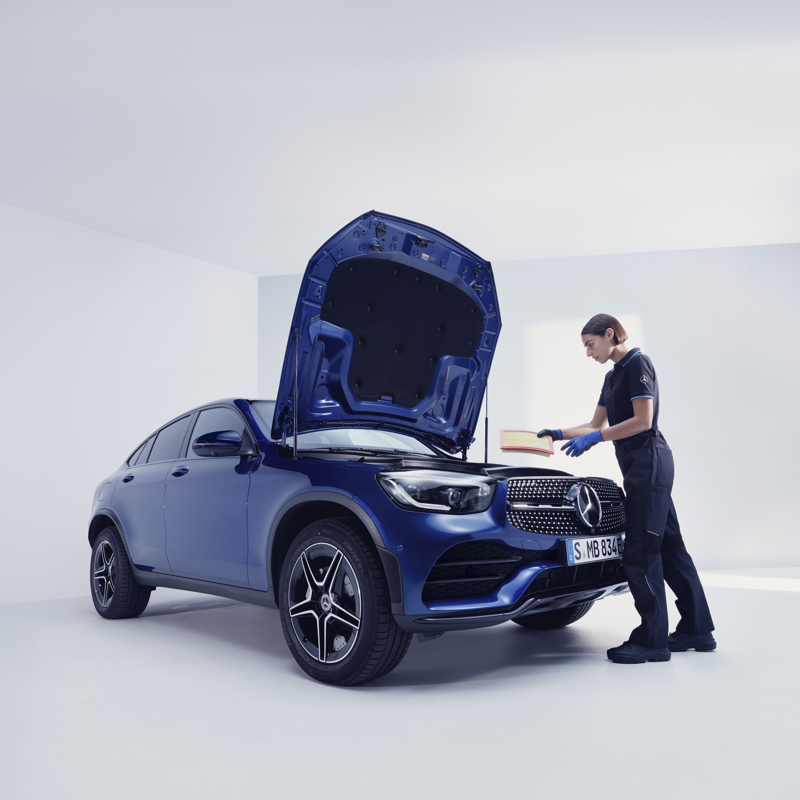 Bir Mercedes-Benz tamircisi bir Mercedes-Benz'i muayene ederken.