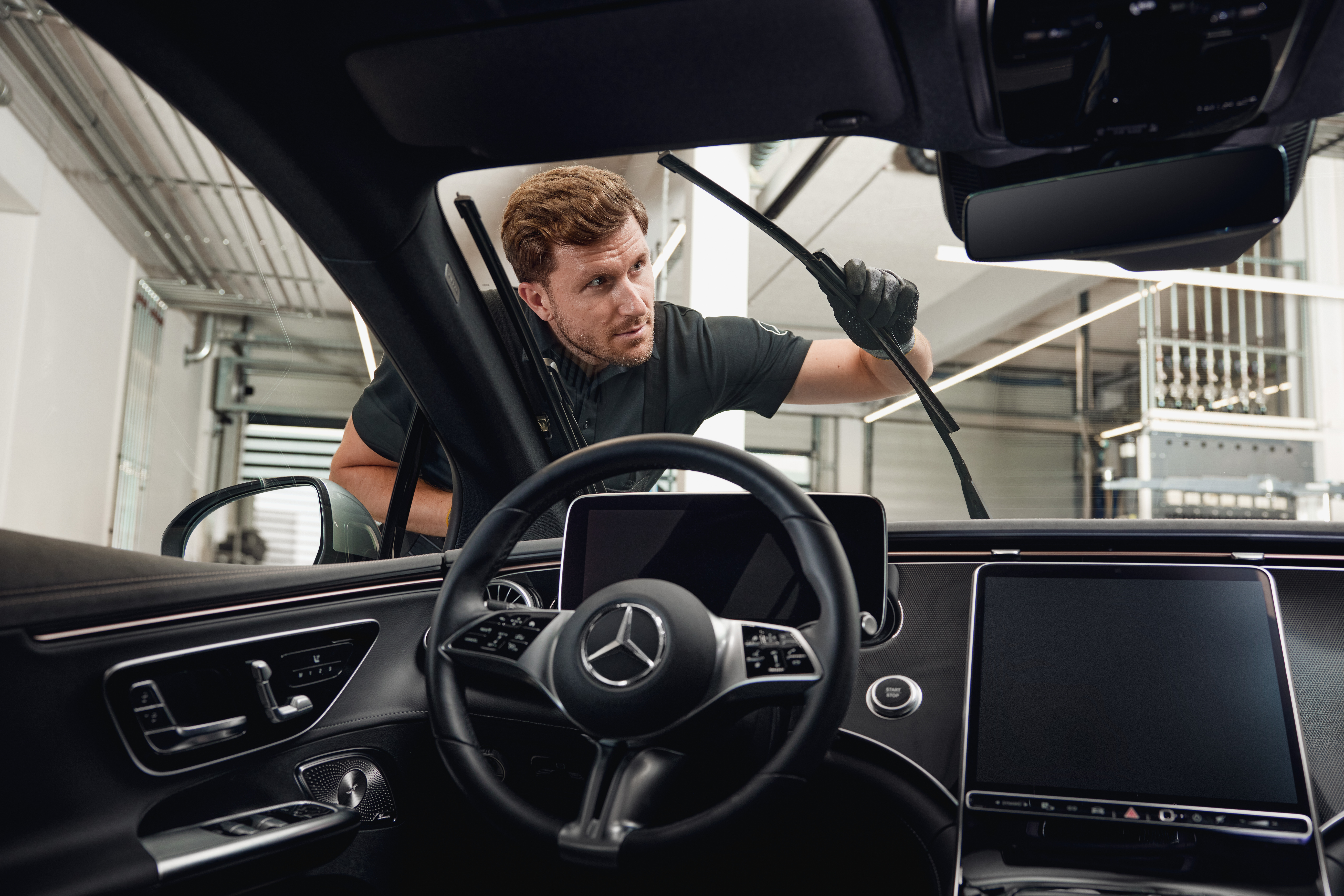 Mercedes-Benz Orijinal Silecek Süpürgeleri Orijinal silecek süpürgelerini değiştiren bir teknisyenle birlikte bir Mercedes-Benz aracının iç görünümü.