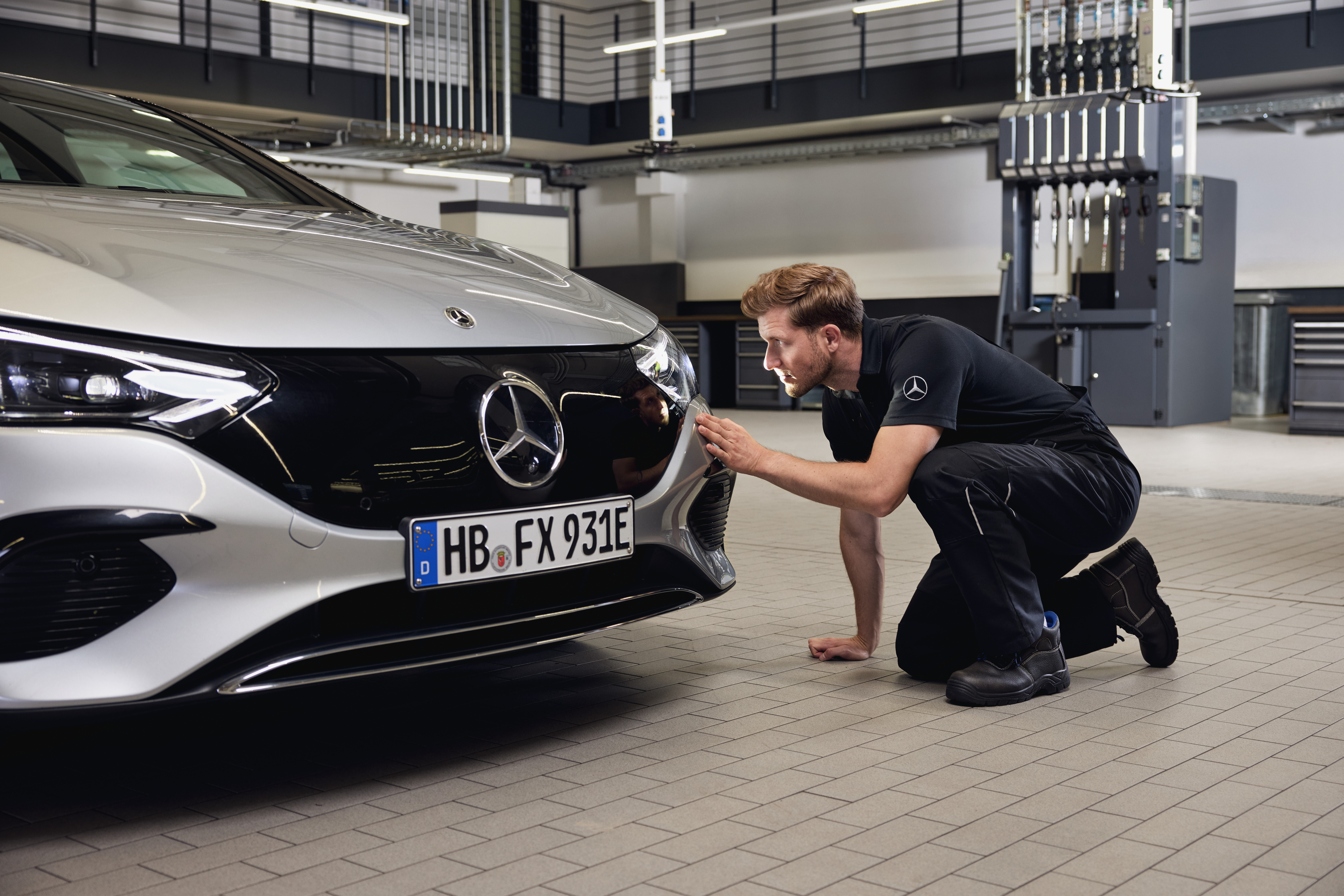 Mercedes-Benz Orijinal Far Değişimi Mercedes-Benz Orijinal Parça değişimi için ayrıntılı bir inceleme yürüten bir teknisyenle birlikte bir Mercedes-Benz aracının ön kısmının yakından görünümü.