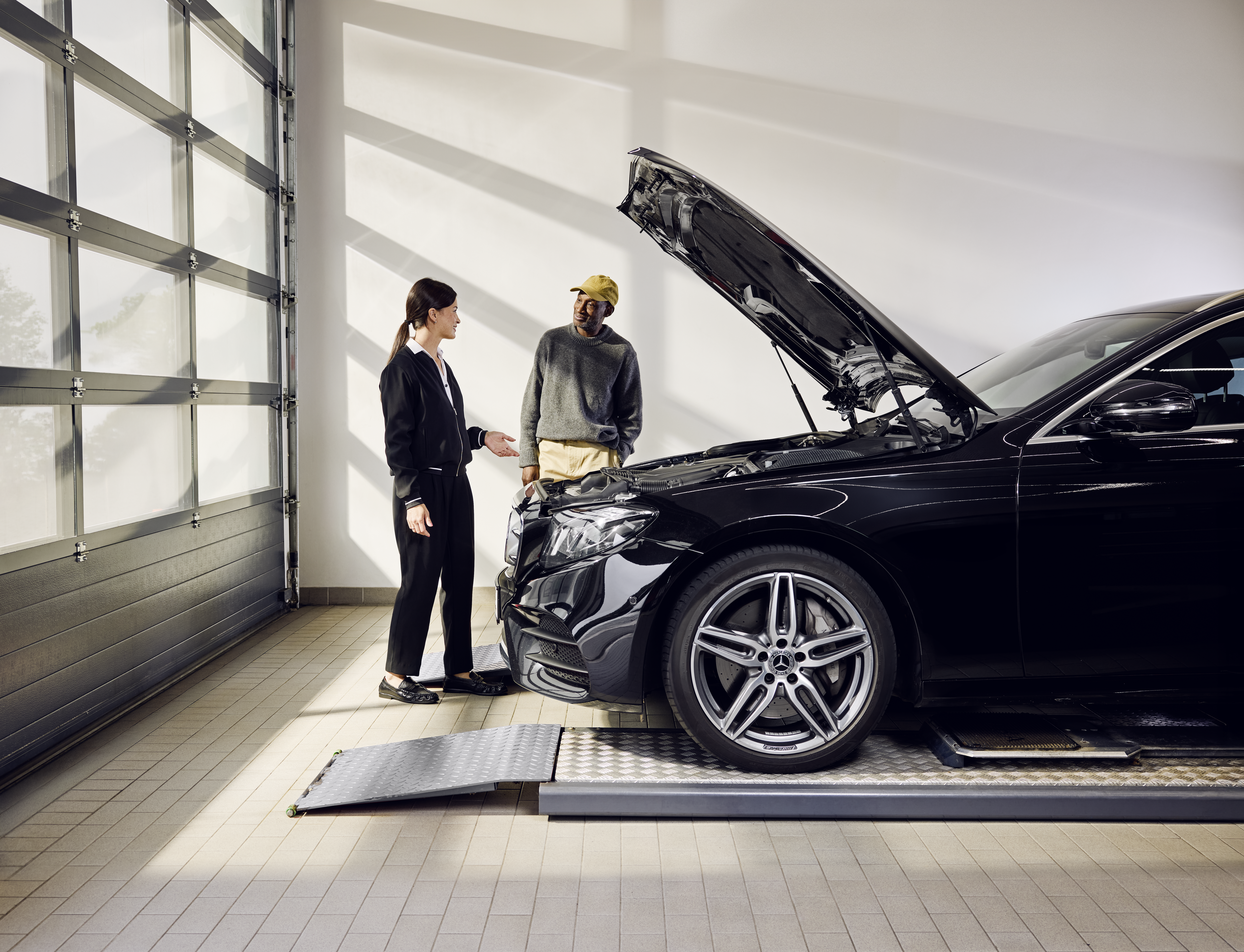 Mercedes-Benz Orijinal Parça Değişimi Bir yetkili serviste orijinal parçaların profesyonel değişimi sırasında kaputu açık olarak servis rampasında pozisyonlandırılmış bir Mercedes‑Benz aracı.