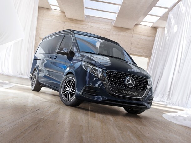 Mercedes-Benz'in Marco Polo V serisi, beyaz perdelerle çevrili iyi ışık alan bir salonda duruyor.