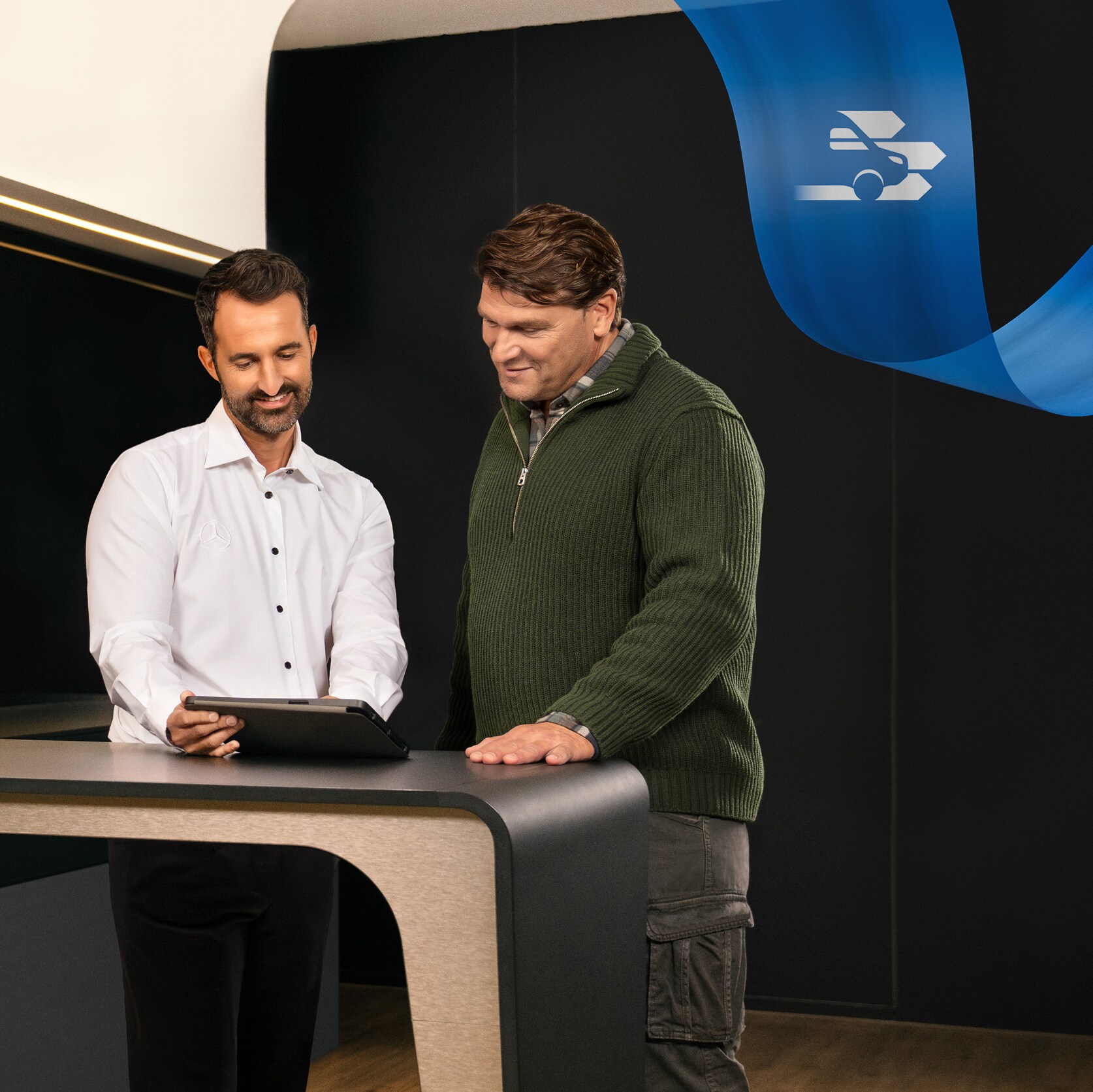 Mercedes-Benz Servis Partneri ofisinin önünde duran iki kişi tablet üzerinde bir şey tartışıyor