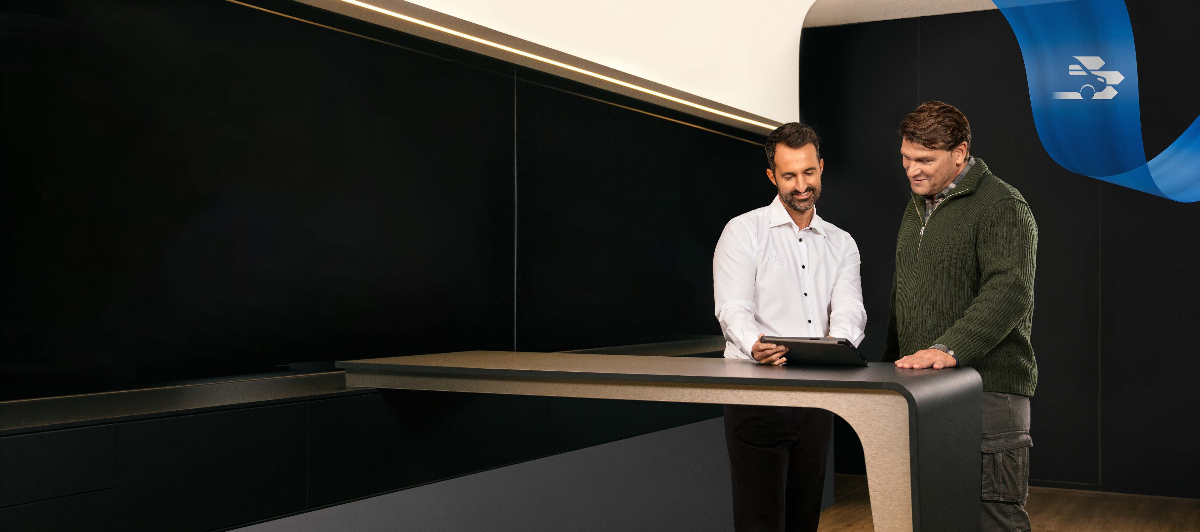 Mercedes-Benz | Konfor | Servis Partneri Mercedes-Benz Servis Partneri ofisinin önünde duran iki kişi tablet üzerinde bir şey tartışıyor
