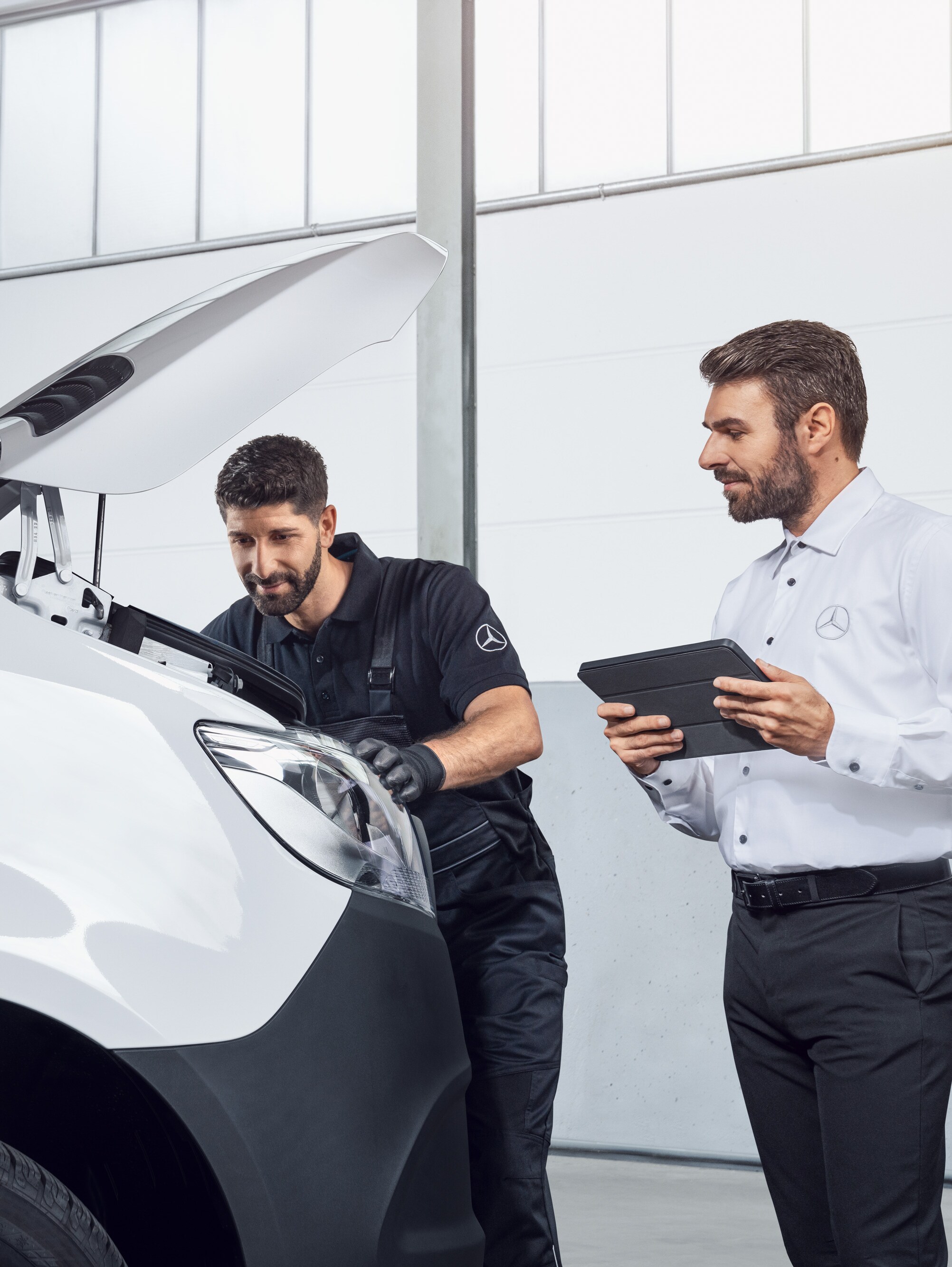 Tablet ve açık motor kaputu ile bir Mercedes Sprinter'ı test eden iki adam, konu: Mercedes-Benz Sprinter yedek parçaları.