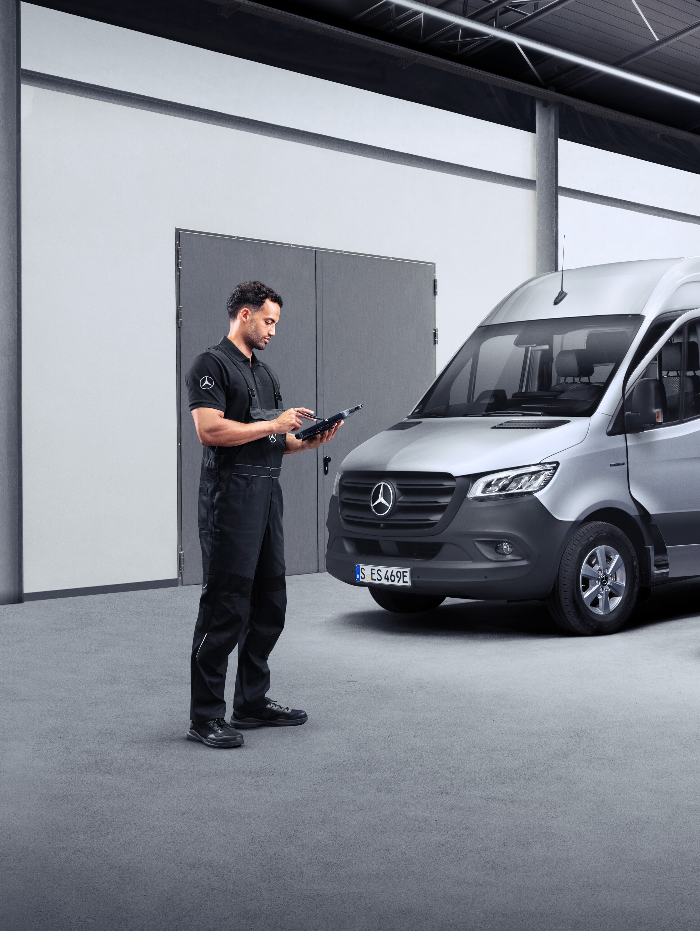 Tablette iki elektrikli hafif ticari aracın önünde bulunan bir teknisyen