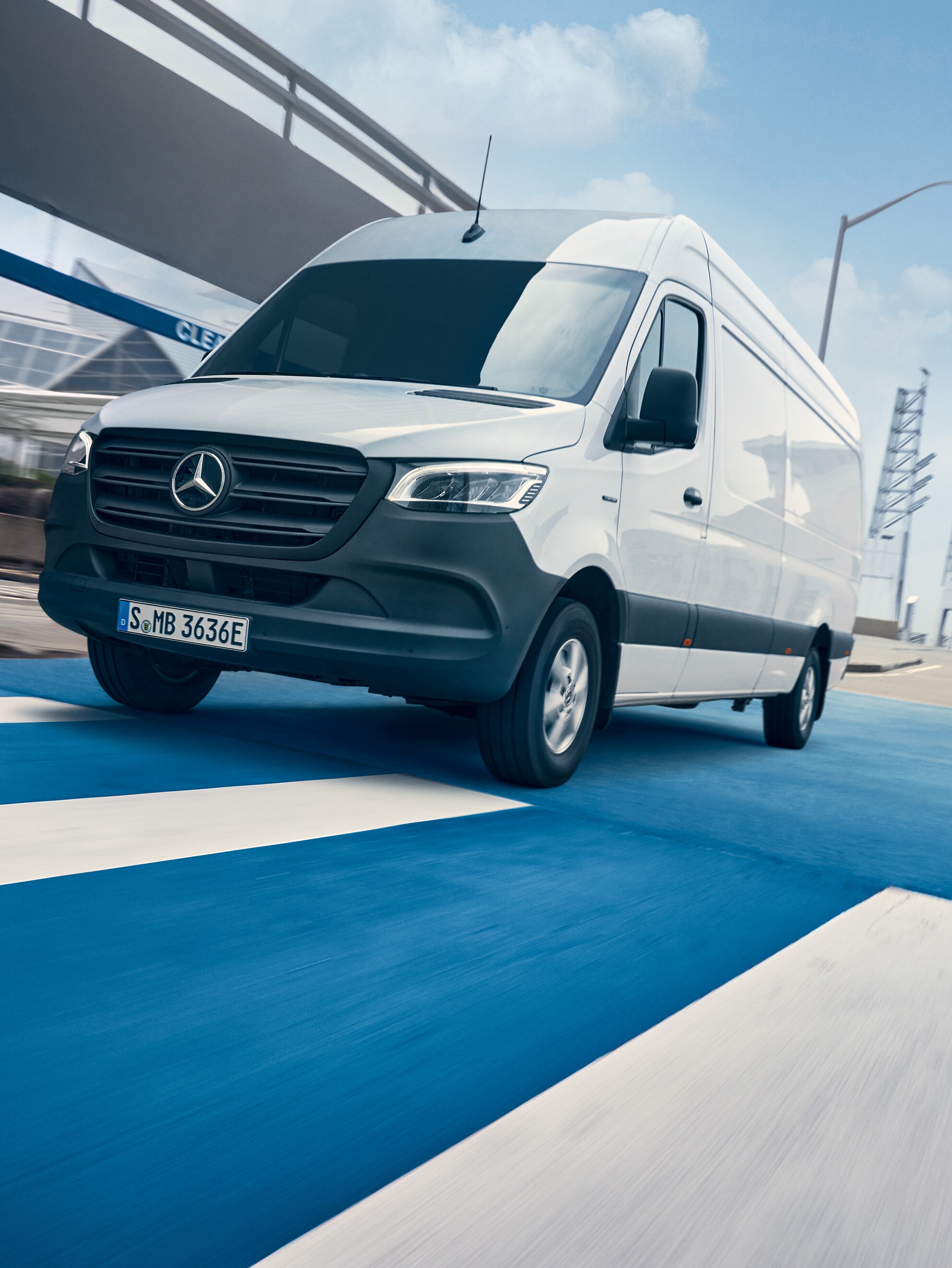 Beyaz bir Mercedes-Benz Sprinter sürücüsü şehir içinde yolda sürüş yapıyor.