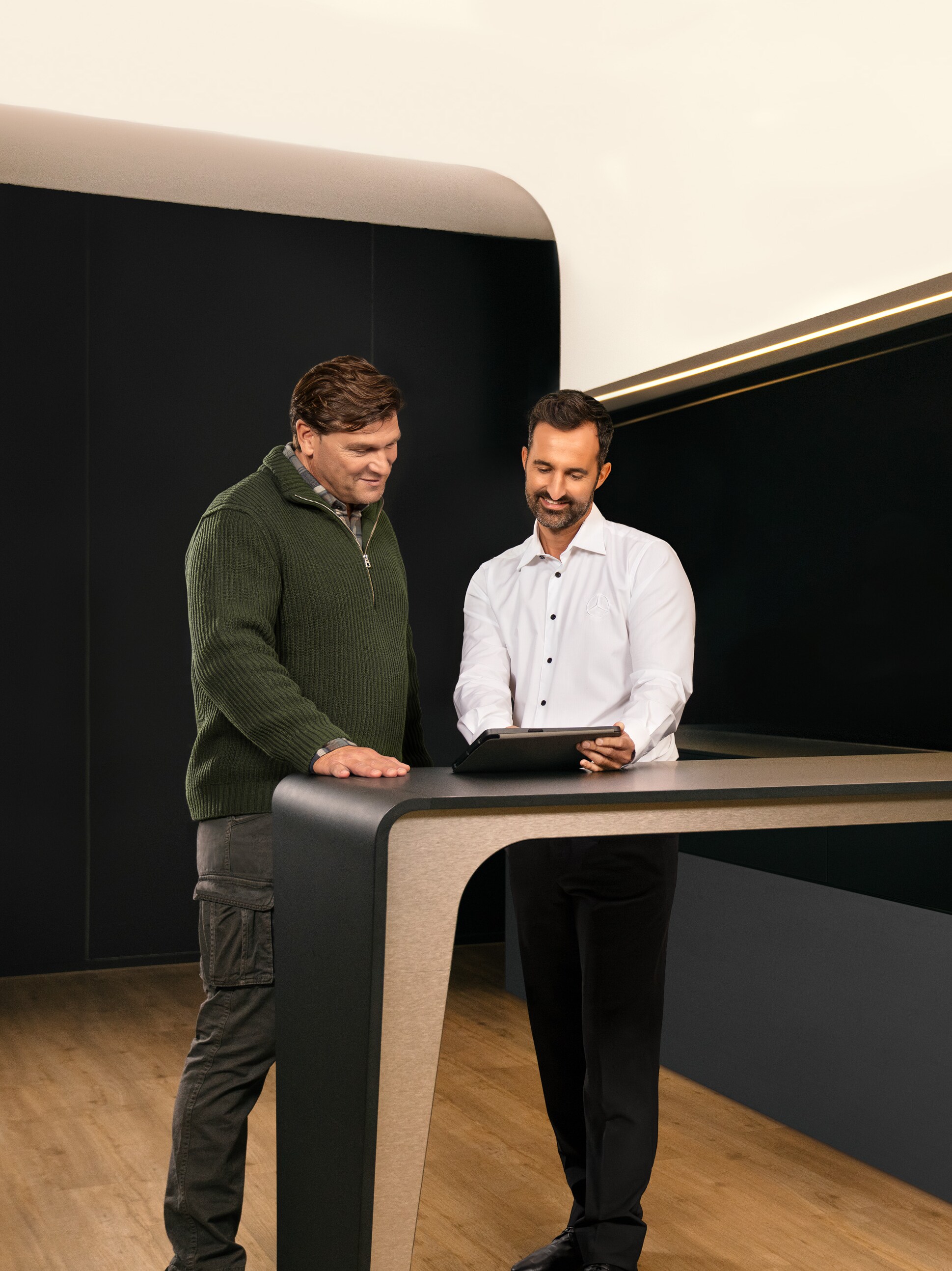 Bir tablet üzerinde Mercedes-Benz ticari araç servisleri hakkında konuşan iki adam.