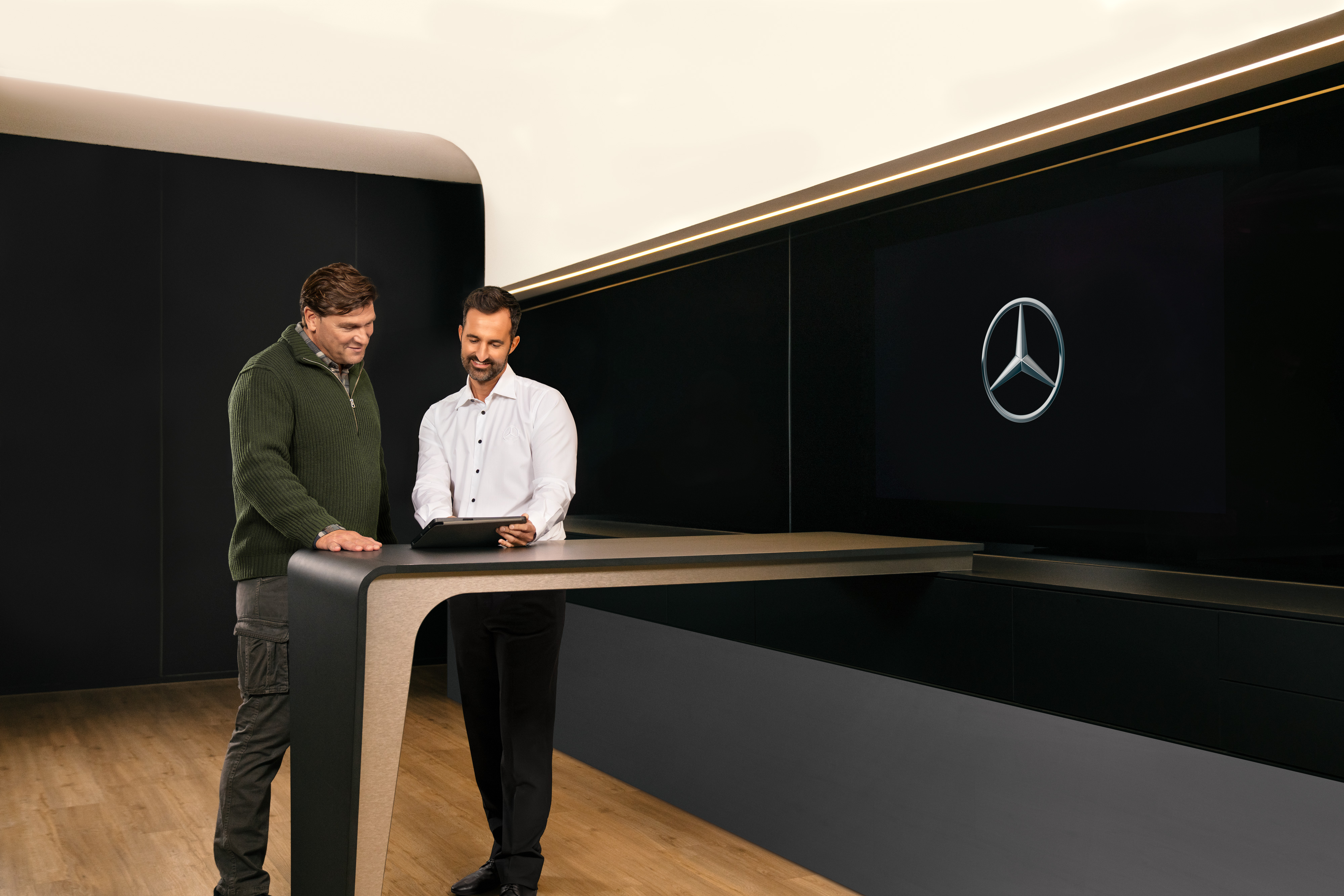 Mercedes-Benz | Hizmetlere Genel Bakış | ServiceCare Bir tablet üzerinde Mercedes-Benz ticari araç servisleri hakkında konuşan iki adam.