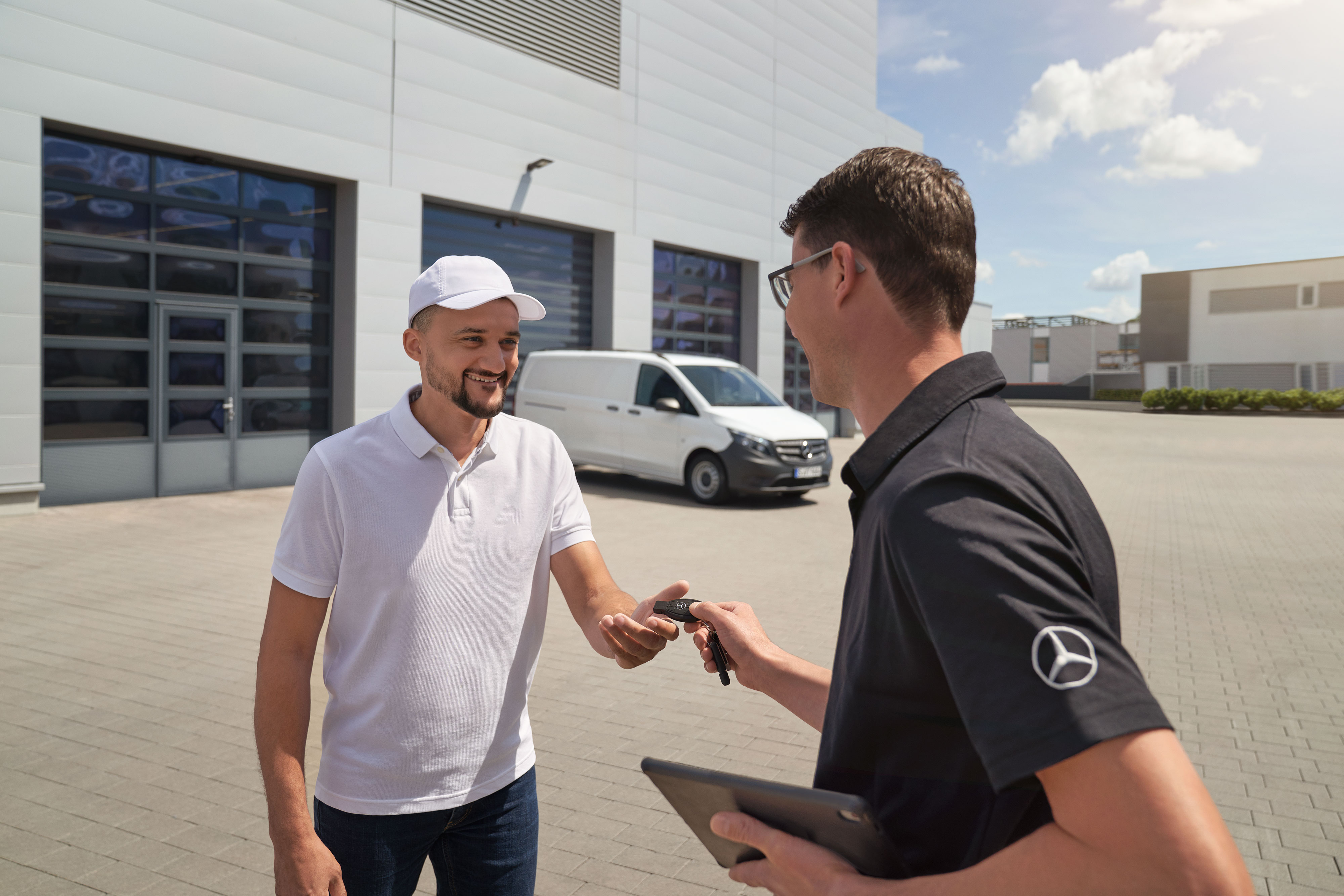 Mercedes-Benz | Hafif Ticari Araç ServiceCare | Ek seçenekler Arka planda beyaz bir Mercedes-Benz Vito hafif ticari araç ile bir teknisyen anahtarı müşteriye teslim ediyor.