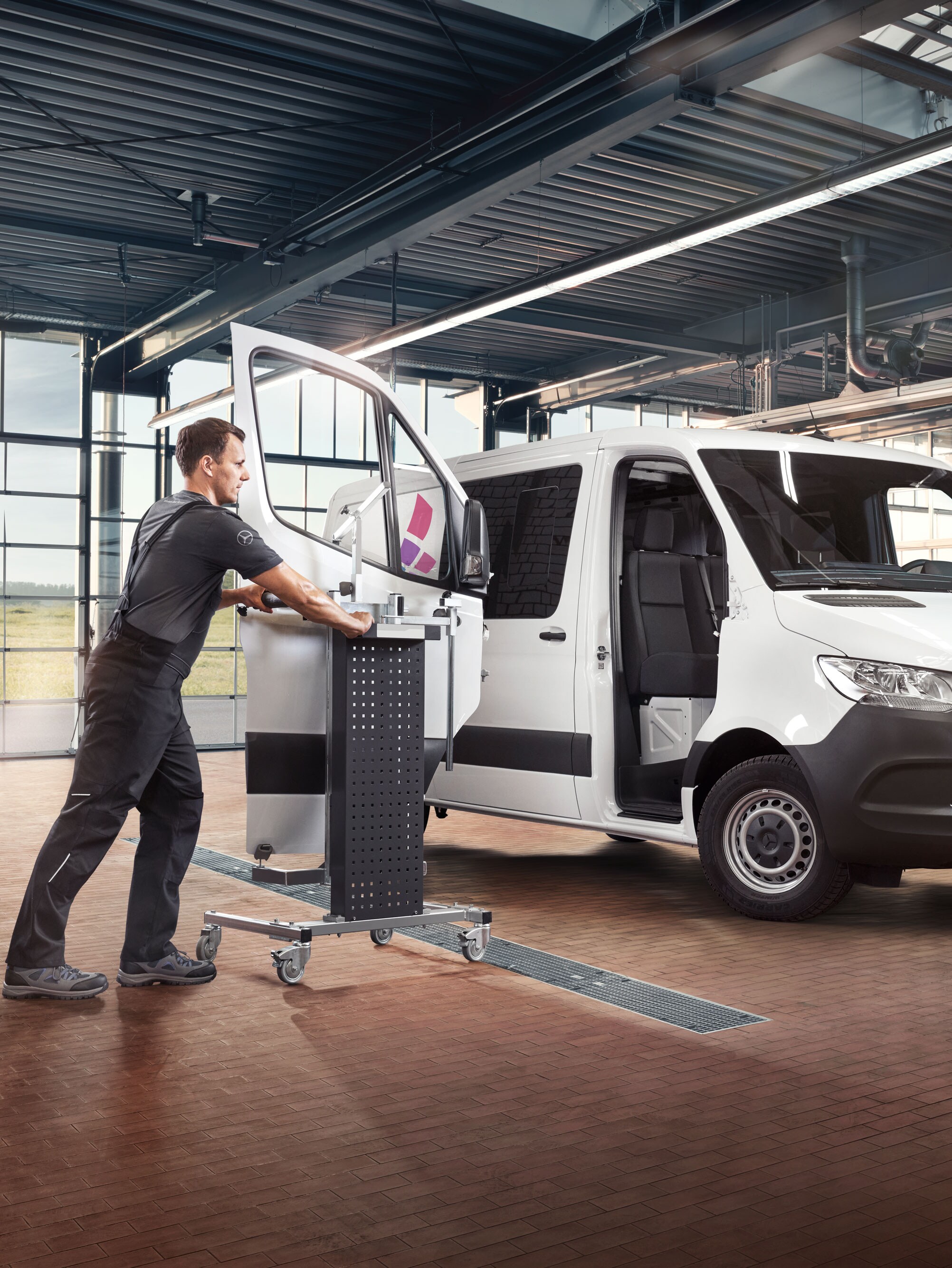 Mekanik teknisyeni beyaz bir Mercedes-Benz Sprinter'da kapıyı yerleştiriyor.