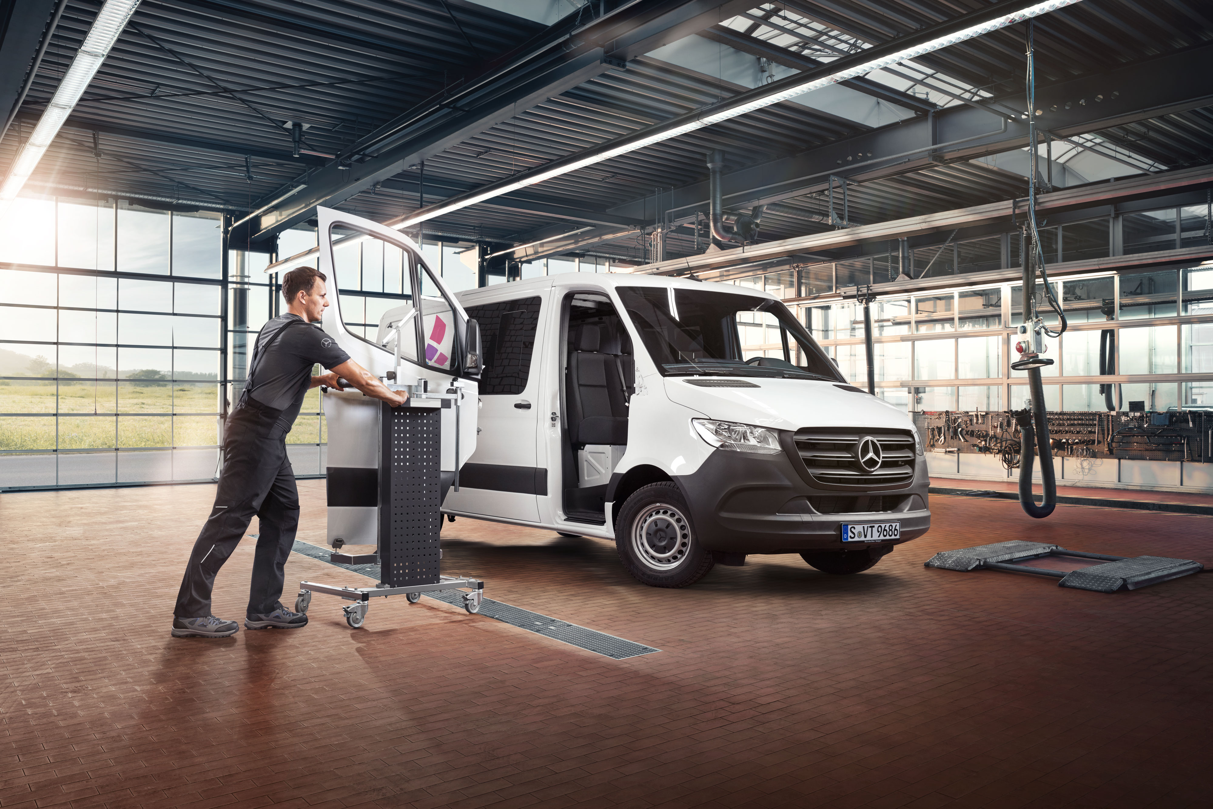 Mercedes-Benz | Onarım Mekanik teknisyeni beyaz bir Mercedes-Benz Sprinter'da kapıyı yerleştiriyor.